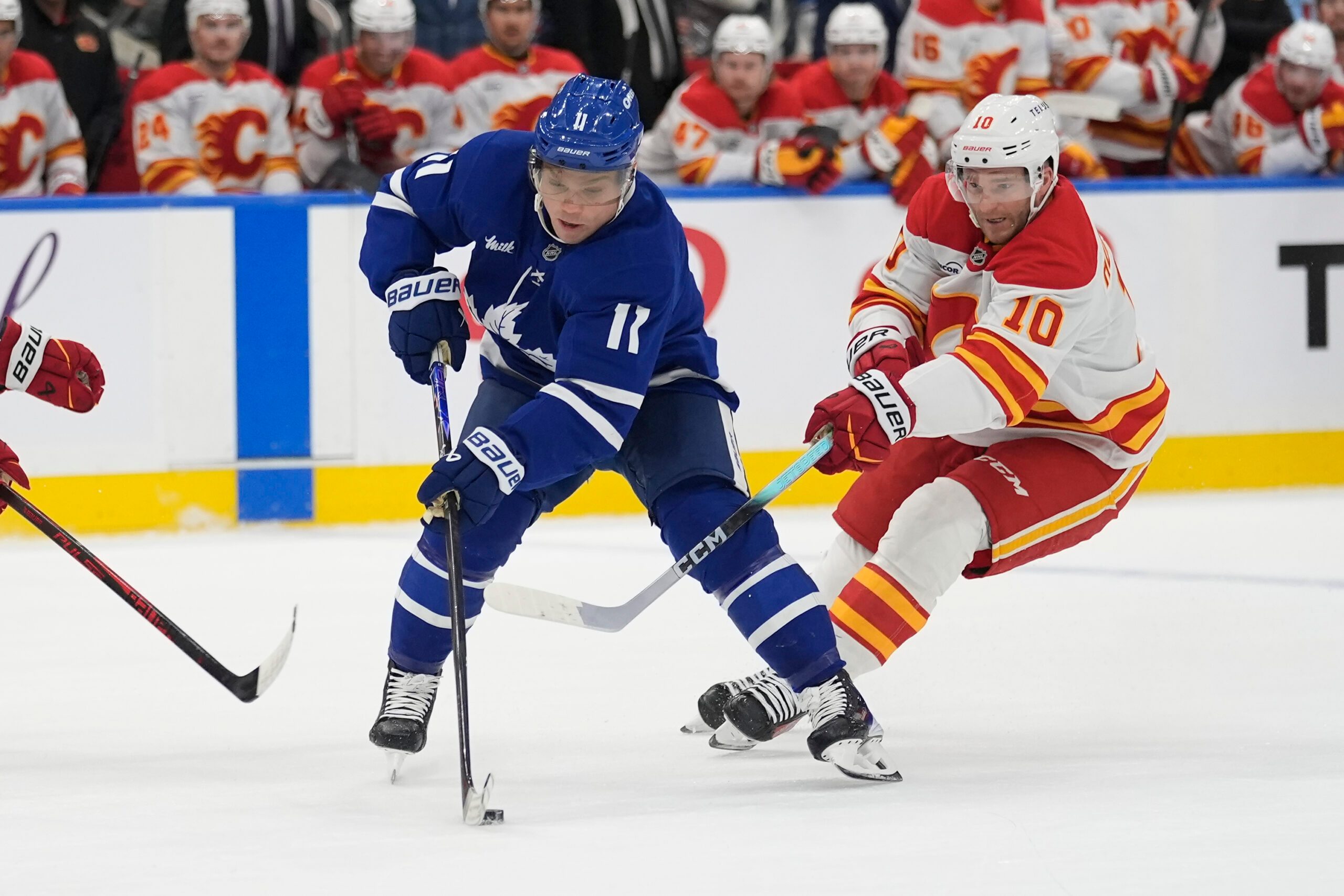 Oct 28, 2025; Toronto, Ontario, CAN; Toronto Maple Leafs forward Max Domi (11) controls the puck against Calgary Flames forward Jonathan Huberdeau (10) during the first period at Scotiabank Arena. Mandatory Credit: John E. Sokolowski-Imagn Images