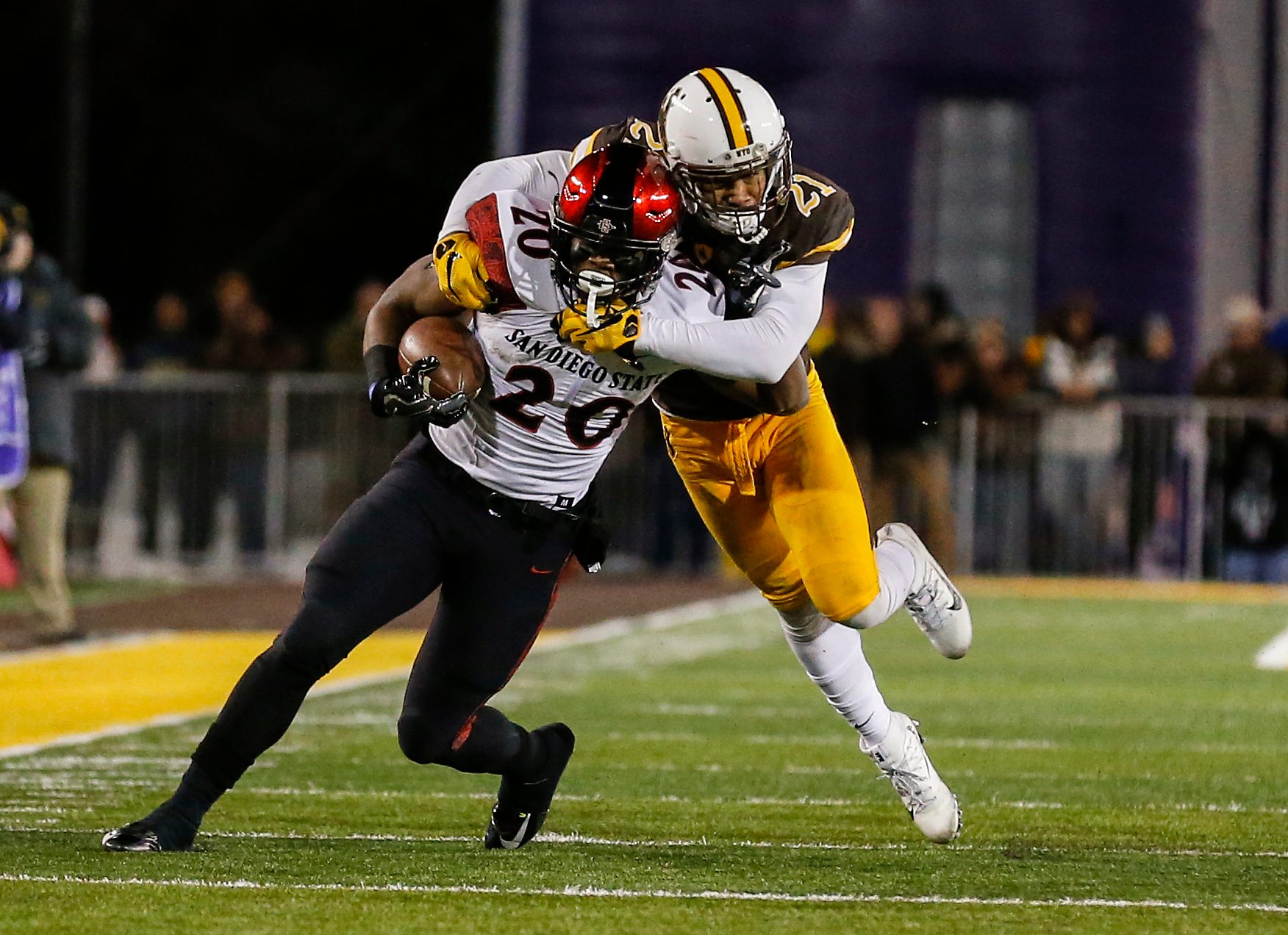 Dec 3, 2016; Laramie, WY, USA; San Diego State Aztecs running back Rashaad Penny (20) is tackled by Wyoming Cowboys cornerback Antonio Hull (21) during the second quarter at the Mountain West Championship college football game at War Memorial Stadium. Mandatory Credit: Troy Babbitt-Imagn Images