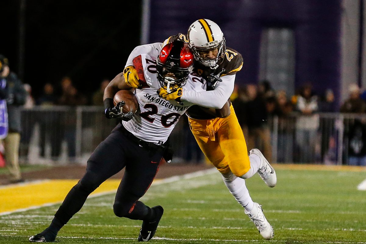 Dec 3, 2016; Laramie, WY, USA; San Diego State Aztecs running back Rashaad Penny (20) is tackled by Wyoming Cowboys cornerback Antonio Hull (21) during the second quarter at the Mountain West Championship college football game at War Memorial Stadium. Mandatory Credit: Troy Babbitt-Imagn Images