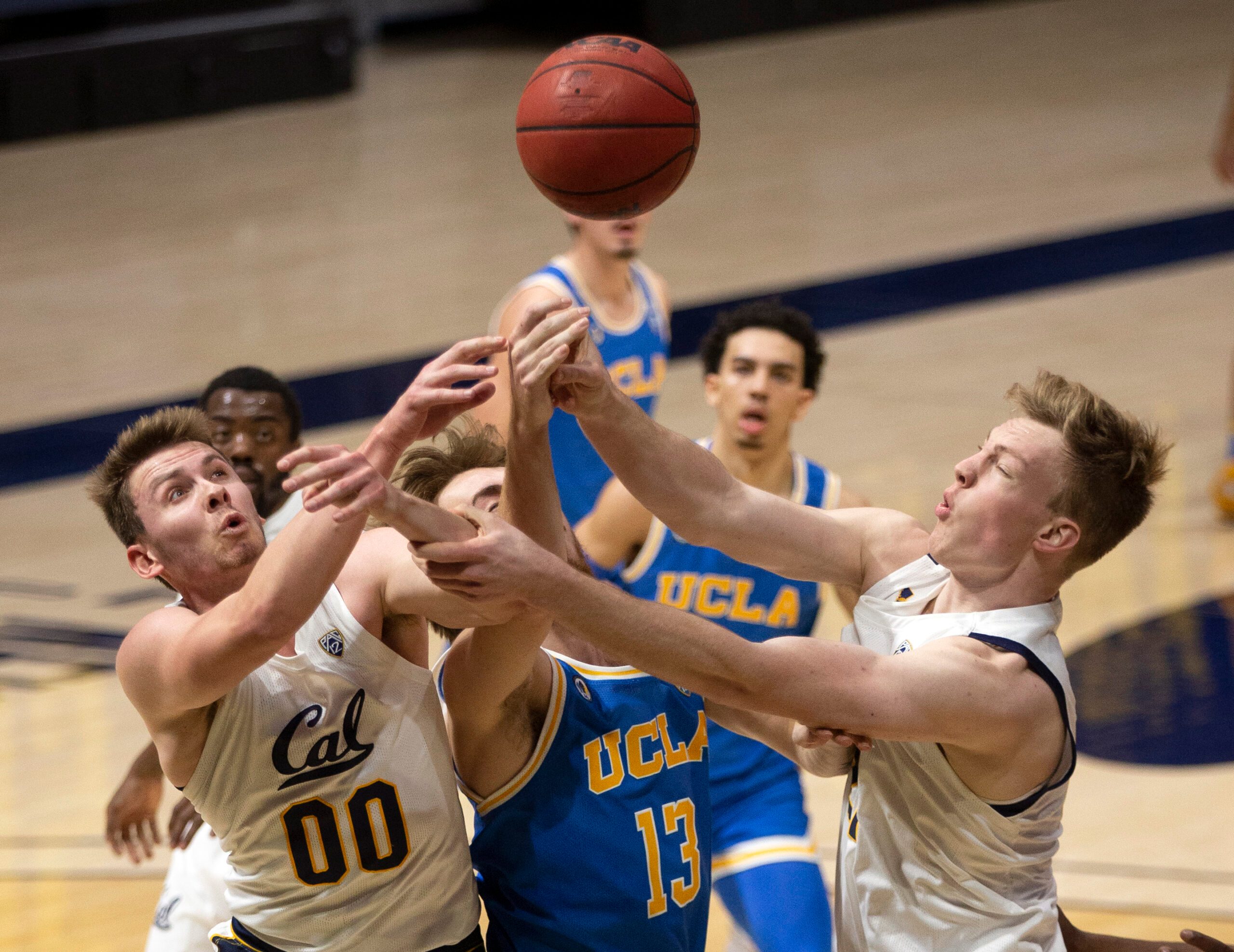 Jan 21, 2021; Berkeley, California, USA; UCLA Bruins guard Jake Kyman (13) vies for a rebound with California Golden Bears defenders Ryan Betley (00) and Lars Thiemann (21) during the first half of an NCAA men s college basketball game at Haas Pavilion. Mandatory Credit: D. Ross Cameron-Imagn Images