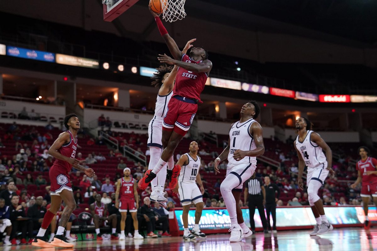 Feb 27, 2024; Fresno, California, USA; Fresno State Bulldogs guard Jalen Weaver (5) makes a layup in front of Utah State Aggies guard Javon Jackson (22) in the second half at the Save Mart Center. Mandatory Credit: Cary Edmondson-Imagn Images