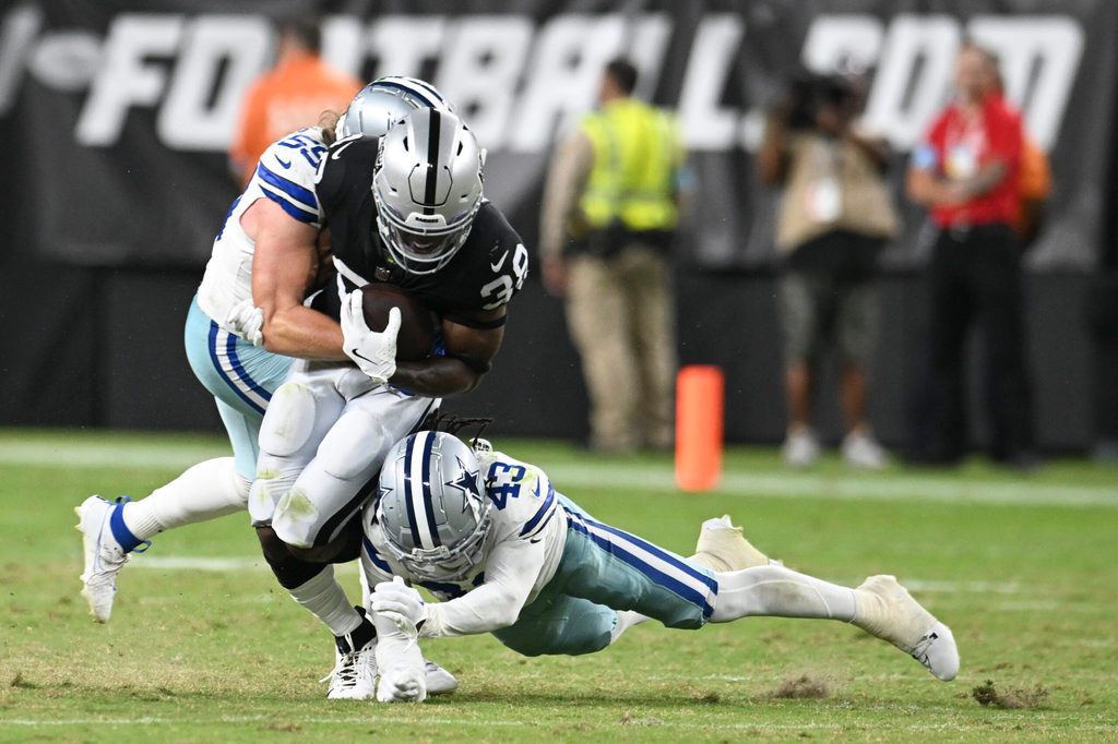 Aug 17, 2024; Paradise, Nevada, USA; Las Vegas Raiders running back Brittain Brown (38) is tackled by Dallas Cowboys linebacker Willie Harvey Jr. (55) and cornerback Kemon Hall (43) in the fourth quarter at Allegiant Stadium. Mandatory Credit: Candice Ward-Imagn Images
