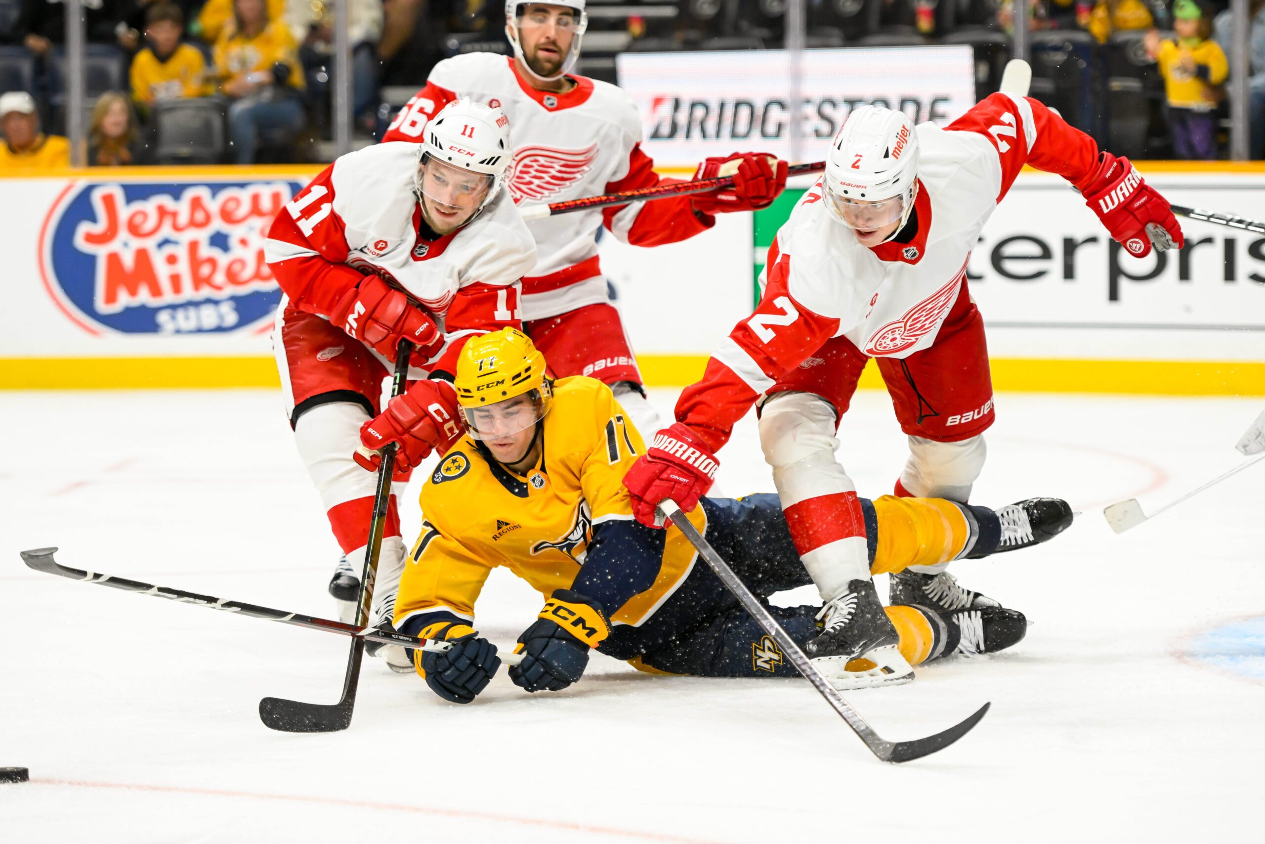 Oct 19, 2024; Nashville, Tennessee, USA;  Nashville Predators right wing Luke Evangelista (77), Detroit Red Wings right wing Vladimir Tarasenko (11), and defenseman Olli Maatta (2) fight for the puck during the third period at Bridgestone Arena. Mandatory Credit: Steve Roberts-Imagn Images
