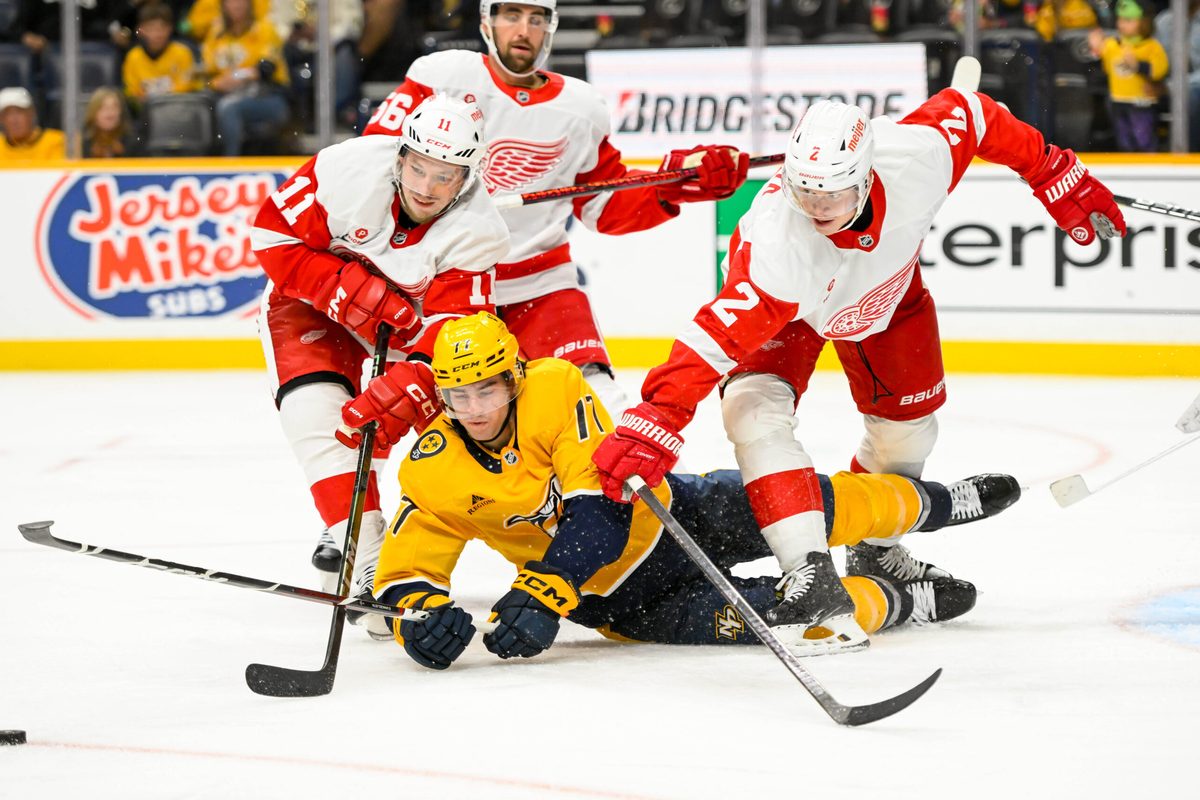 Oct 19, 2024; Nashville, Tennessee, USA; Nashville Predators right wing Luke Evangelista (77), Detroit Red Wings right wing Vladimir Tarasenko (11), and defenseman Olli Maatta (2) fight for the puck during the third period at Bridgestone Arena. Mandatory Credit: Steve Roberts-Imagn Images