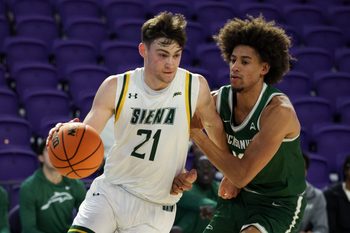 Nov 26, 2024; Fort Myers, Florida, USA; Siena Saints forward Brendan Coyle (21) drives to the basket past Jacksonville Dolphins forward Zimi Nwokeji (16) in the first half at Suncoast Credit Union Arena. Mandatory Credit: Nathan Ray Seebeck-Imagn Images