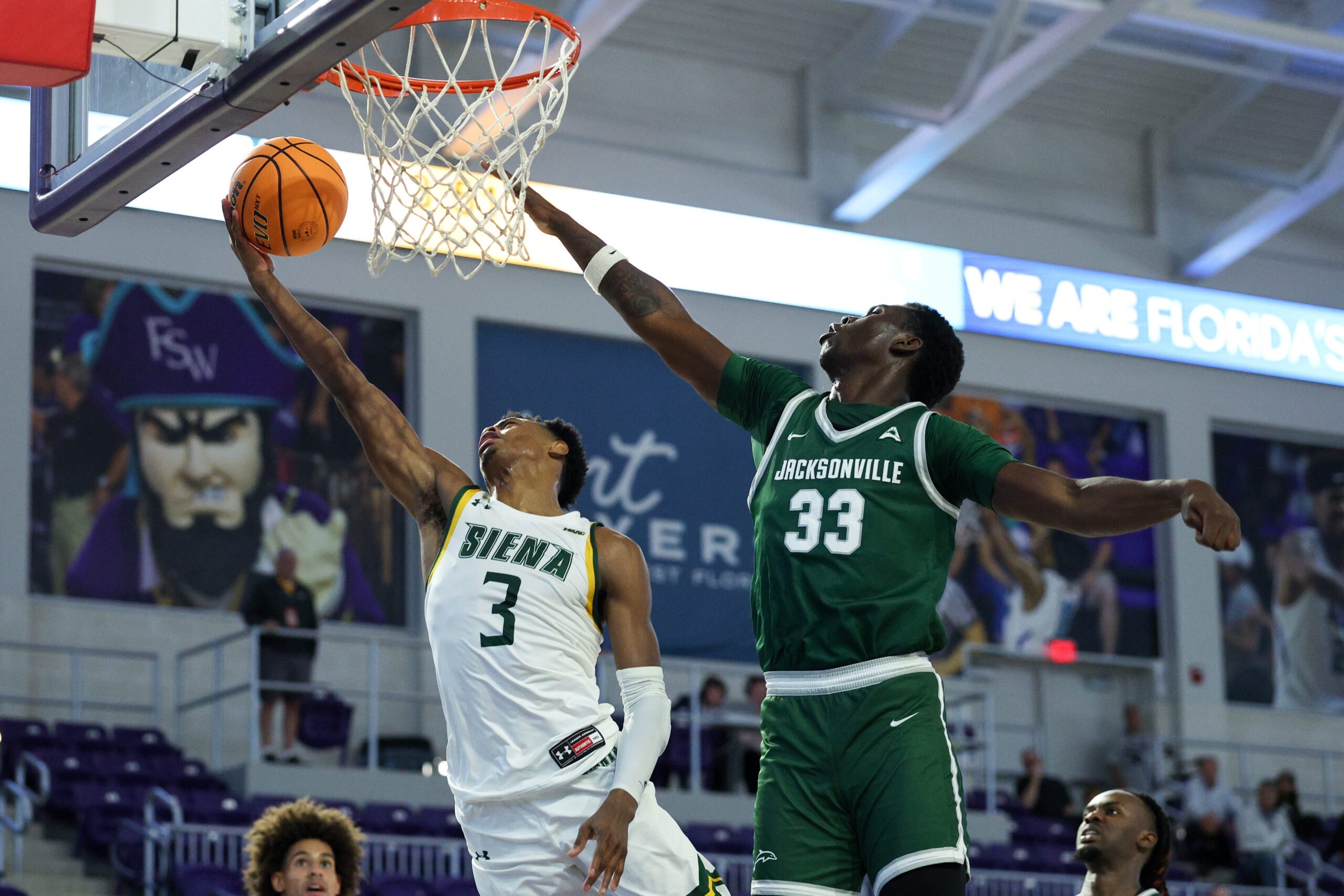 Nov 26, 2024; Fort Myers, Florida, USA; Siena Saints guard Major Freeman (3) drives to the hoop past Jacksonville Dolphins forward Donovan Rivers (33) in the first half at Suncoast Credit Union Arena. Mandatory Credit: Nathan Ray Seebeck-Imagn Images