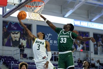 Nov 26, 2024; Fort Myers, Florida, USA; Siena Saints guard Major Freeman (3) drives to the hoop past Jacksonville Dolphins forward Donovan Rivers (33) in the first half at Suncoast Credit Union Arena. Mandatory Credit: Nathan Ray Seebeck-Imagn Images