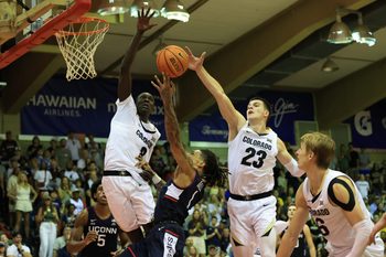 Nov 26, 2024; Lahaina, Hawaii, USA;  Connecticut Huskies guard Solo Ball (1) makes a layup in between Colorado Buffaloes forward Bangot Dak (8) and forward Andrej Jakimovski (23) during the second half of an NCAA college basketball game at Lahaina Civic Center. Mandatory Credit: Marco Garcia-Imagn Images