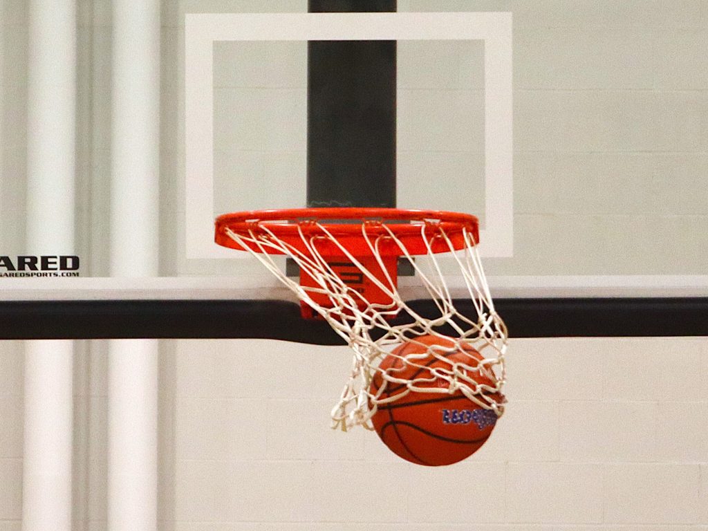 A basketball swishes the net as it goes through the hoop.