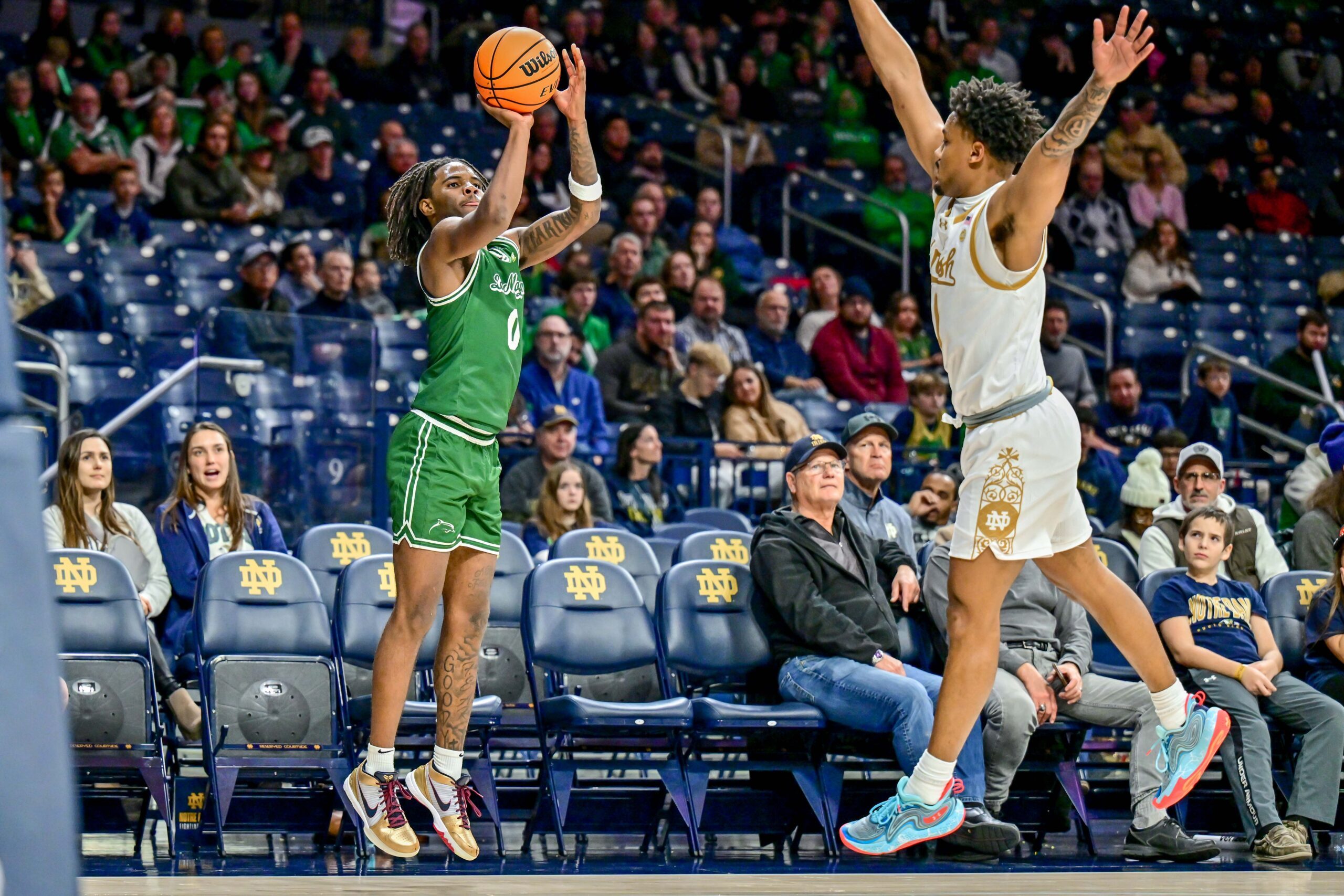Dec 22, 2024; South Bend, Indiana, USA; Le Moyne Dolphins guard AJ Dancler (0) shoots a three point basket as Notre Dame Fighting Irish guard Julian Roper II (1) defends in the second half at the Purcell Pavilion. Mandatory Credit: Matt Cashore-Imagn Images