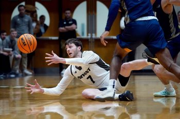Bryant Bulldogs forward Connor Withers reaches out to recover a loose ball as it bounces away from him after hitting the floor after a trip in the first half. The Bulldogs of Bryant University hosted the University of New Hampshire Wildcats in mens basketball action February 8, 2024.