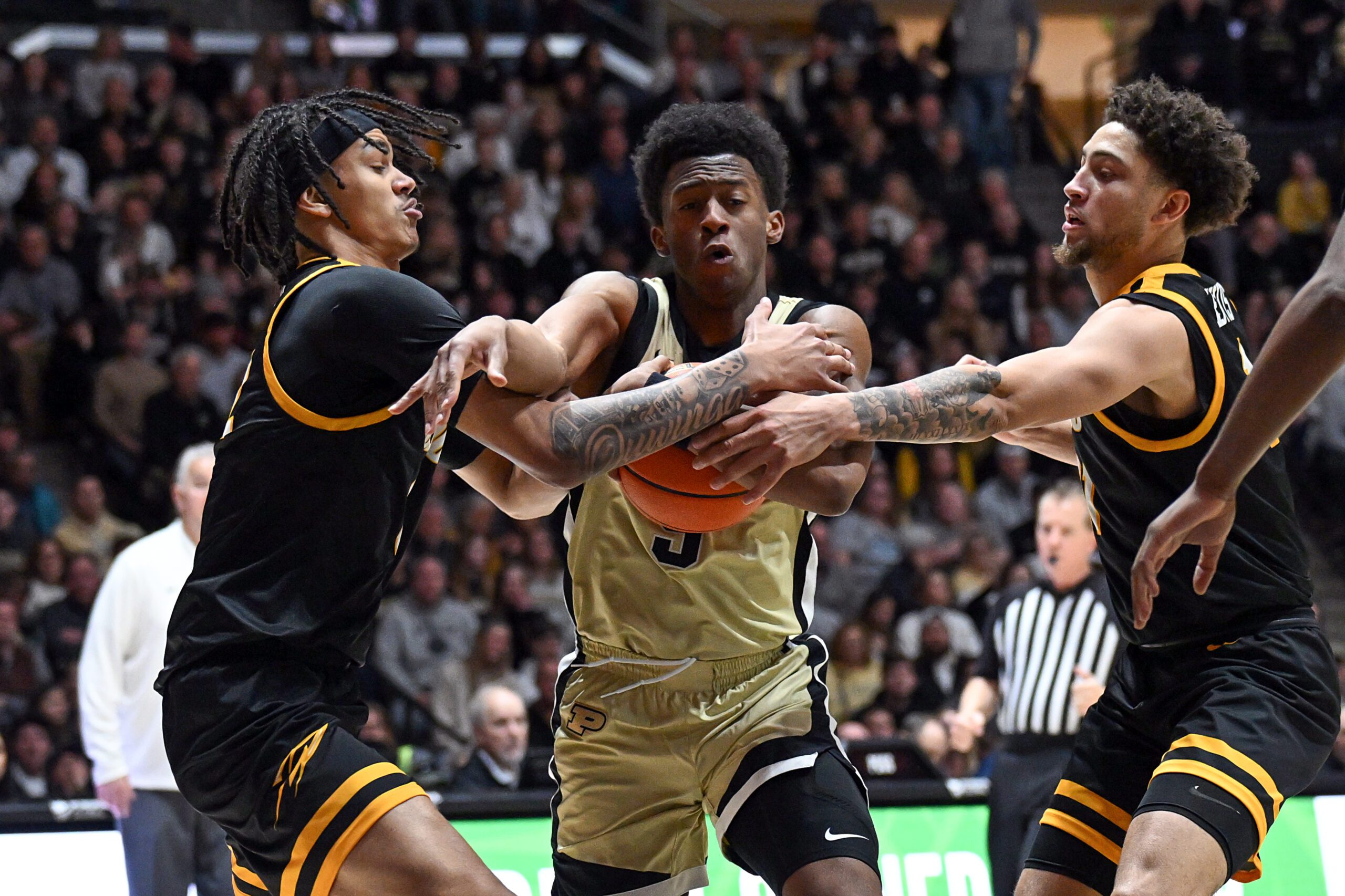 Dec 29, 2024; West Lafayette, Indiana, USA; Purdue Boilermakers guard Myles Colvin (5) pushes through Toledo Rockets guard Sonny Wilson (3), left, and guard Sam Lewis (11), right, during the second half at Mackey Arena. Mandatory Credit: Marc Lebryk-Imagn Images