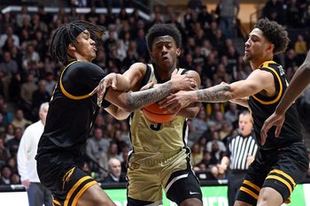 Dec 29, 2024; West Lafayette, Indiana, USA; Purdue Boilermakers guard Myles Colvin (5) pushes through Toledo Rockets guard Sonny Wilson (3), left, and guard Sam Lewis (11), right, during the second half at Mackey Arena. Mandatory Credit: Marc Lebryk-Imagn Images
