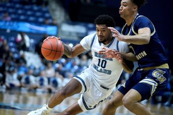 Jamarques Lawrence of URI drives into George Washington defender Dayan Nessah.