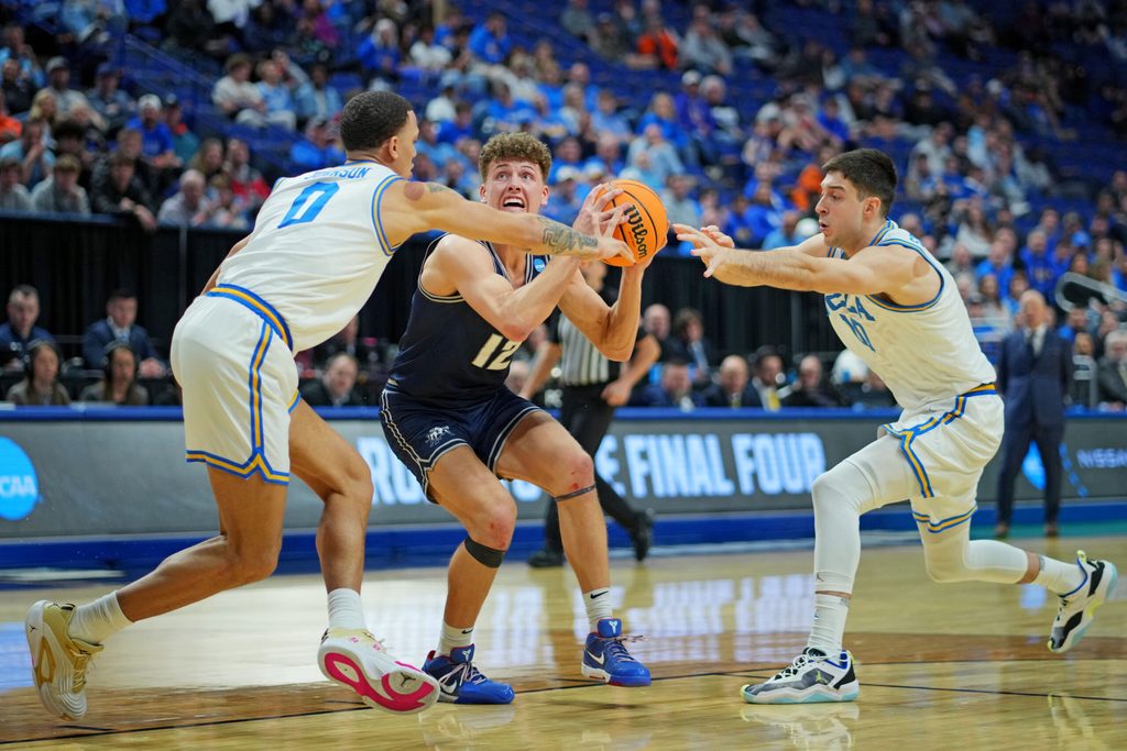 Mar 20, 2025; Lexington, KY, USA; Utah State Aggies guard Mason Falslev (12) drives to the basket against UCLA Bruins guard Kobe Johnson (0) during the second half in the first round of the NCAA Tournament at Rupp Arena. Mandatory Credit: Aaron Doster-Imagn Images