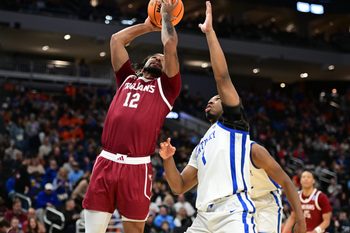 Mar 21, 2025; Milwaukee, WI, USA; Troy Trojans guard Tayton Conerway (12) drives to the hoop past Kentucky Wildcats guard Lamont Butler (1) during the second half at Fiserv Forum. Mandatory Credit: Benny Sieu-Imagn Images