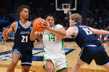 Mar 21, 2025; Seattle, WA, USA; Oregon Ducks guard Jayson Williams-Johnson (14) dribbles the ball past Liberty Flames guard Gabriel McKay (21) during the second half in the first round of the NCAA Tournament at Climate Pledge Arena. Mandatory Credit: Steven Bisig-Imagn Images