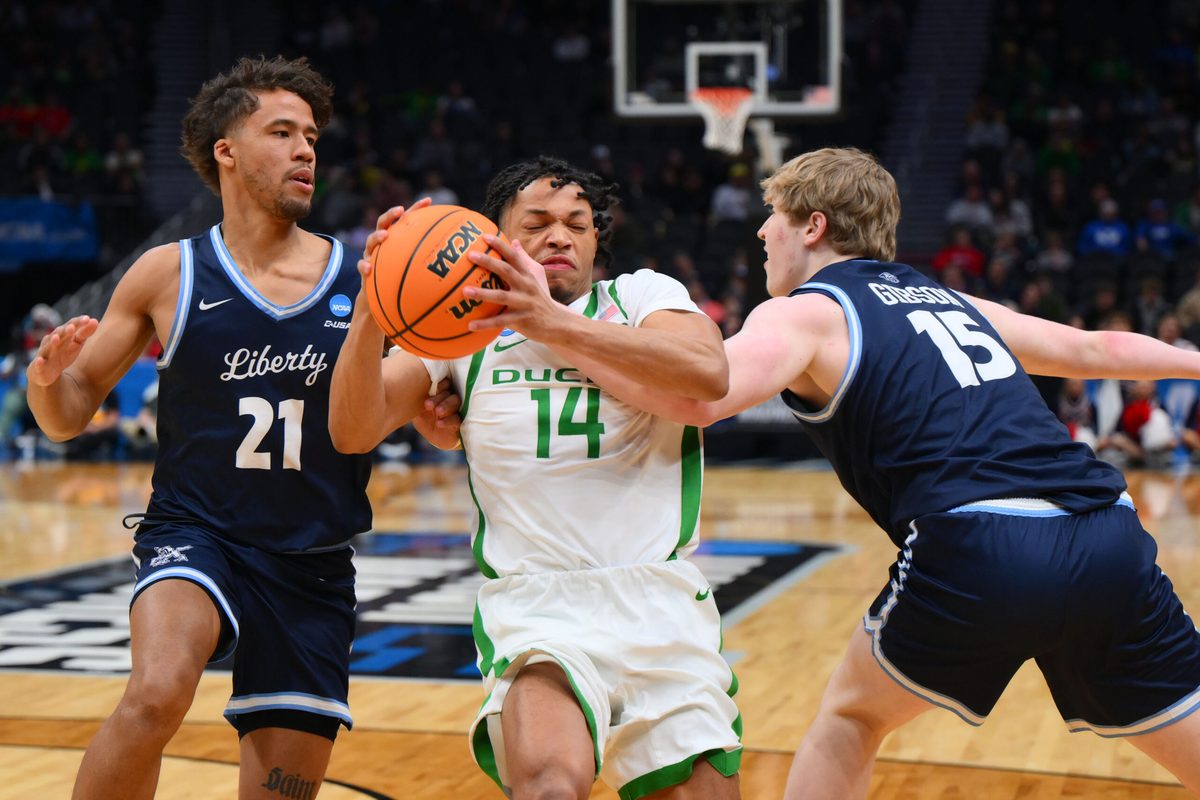 Mar 21, 2025; Seattle, WA, USA; Oregon Ducks guard Jayson Williams-Johnson (14) dribbles the ball past Liberty Flames guard Gabriel McKay (21) during the second half in the first round of the NCAA Tournament at Climate Pledge Arena. Mandatory Credit: Steven Bisig-Imagn Images