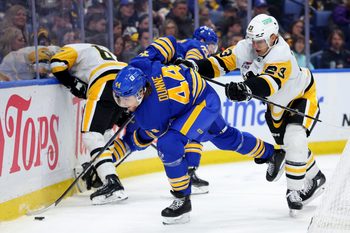 Mar 27, 2025; Buffalo, New York, USA;  Pittsburgh Penguins defenseman Vladislav Kolyachonok (23) checks Buffalo Sabres center Josh Dunne (44) as he plays the puck during the second period at KeyBank Center. Mandatory Credit: Timothy T. Ludwig-Imagn Images