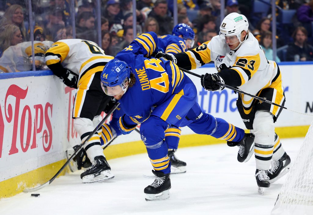 Mar 27, 2025; Buffalo, New York, USA; Pittsburgh Penguins defenseman Vladislav Kolyachonok (23) checks Buffalo Sabres center Josh Dunne (44) as he plays the puck during the second period at KeyBank Center. Mandatory Credit: Timothy T. Ludwig-Imagn Images