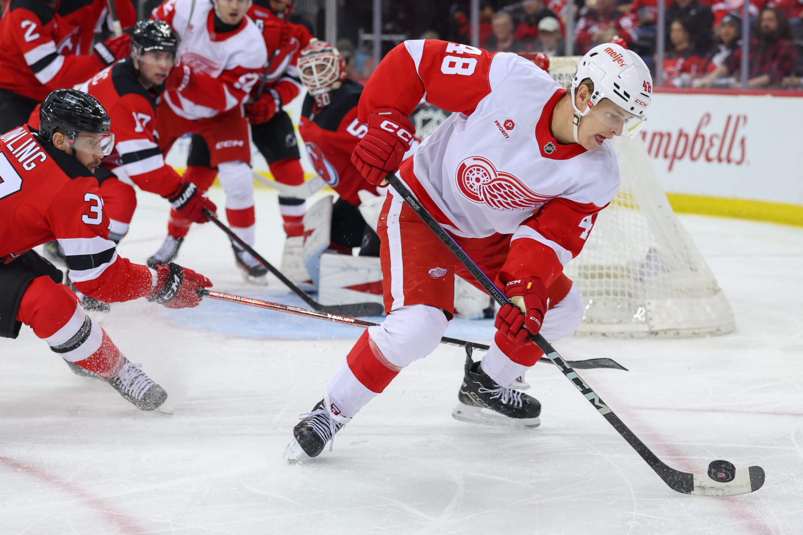 Apr 16, 2025; Newark, New Jersey, USA; Detroit Red Wings right wing Jonatan Berggren (48) plays the puck as New Jersey Devils center Justin Dowling (37) defends during the first period at Prudential Center. Mandatory Credit: Ed Mulholland-Imagn Images