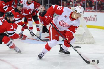 Apr 16, 2025; Newark, New Jersey, USA; Detroit Red Wings right wing Jonatan Berggren (48) plays the puck as New Jersey Devils center Justin Dowling (37) defends during the first period at Prudential Center. Mandatory Credit: Ed Mulholland-Imagn Images