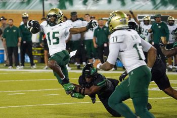 Oct 10, 2025; Denton, Texas, USA; South Florida Bulls running back Alvon Isaac (15) is tripped up by North Texas Mean Green safety Patrick Smith-Young (12) during the second half of a game at DATCU Stadium. Mandatory Credit: Raymond Carlin III-Imagn Images