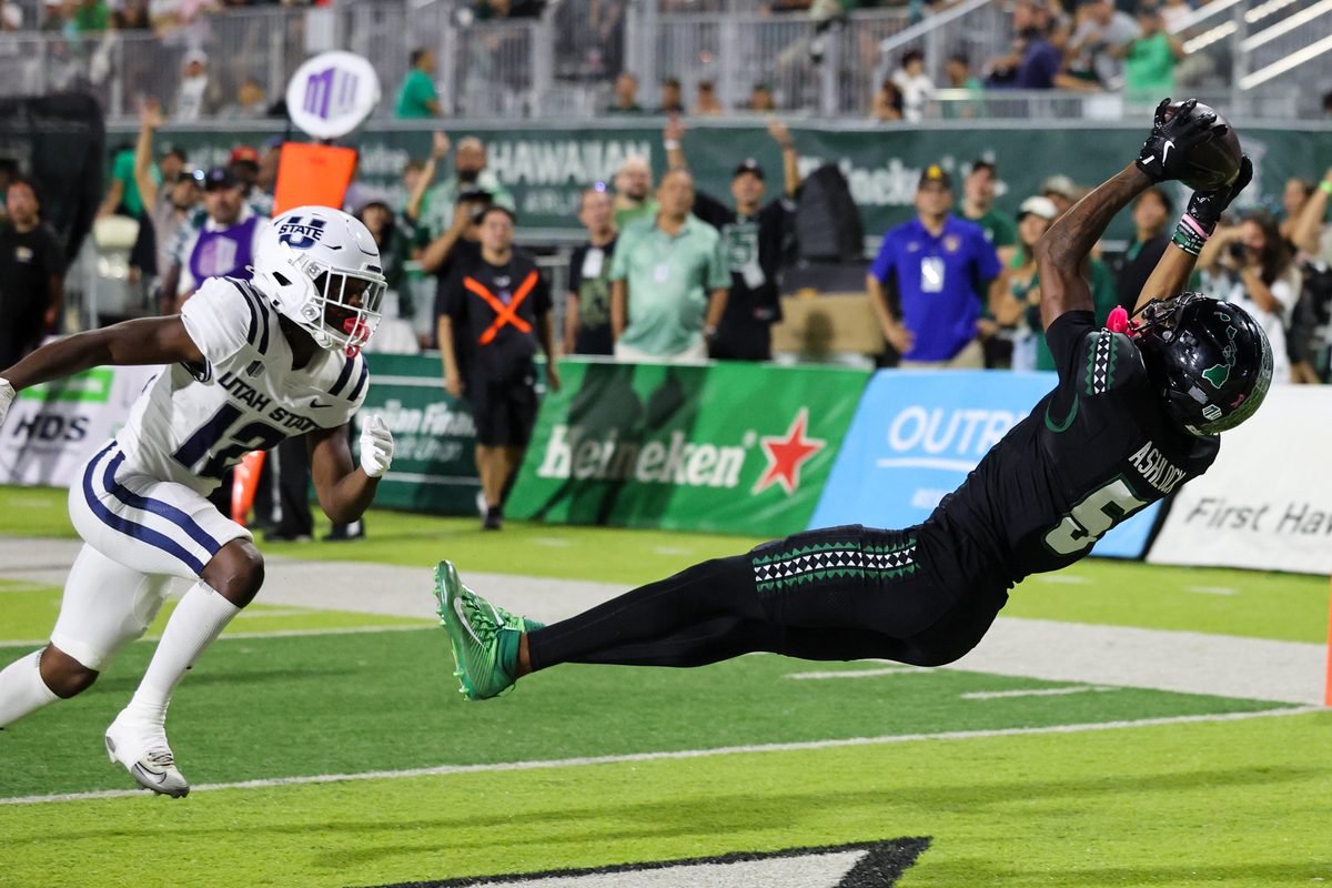 Oct 11, 2025; Honolulu, Hawaii, USA; Hawaii Rainbow Warriors wide receiver Pofele Ashlock (5) pulls in a touchdown catch over Utah State Aggies safety Bobby Arnold (12) during the first half at Clarence T.C. Ching Athletics Complex. Mandatory Credit: Marco Garcia-Imagn Images