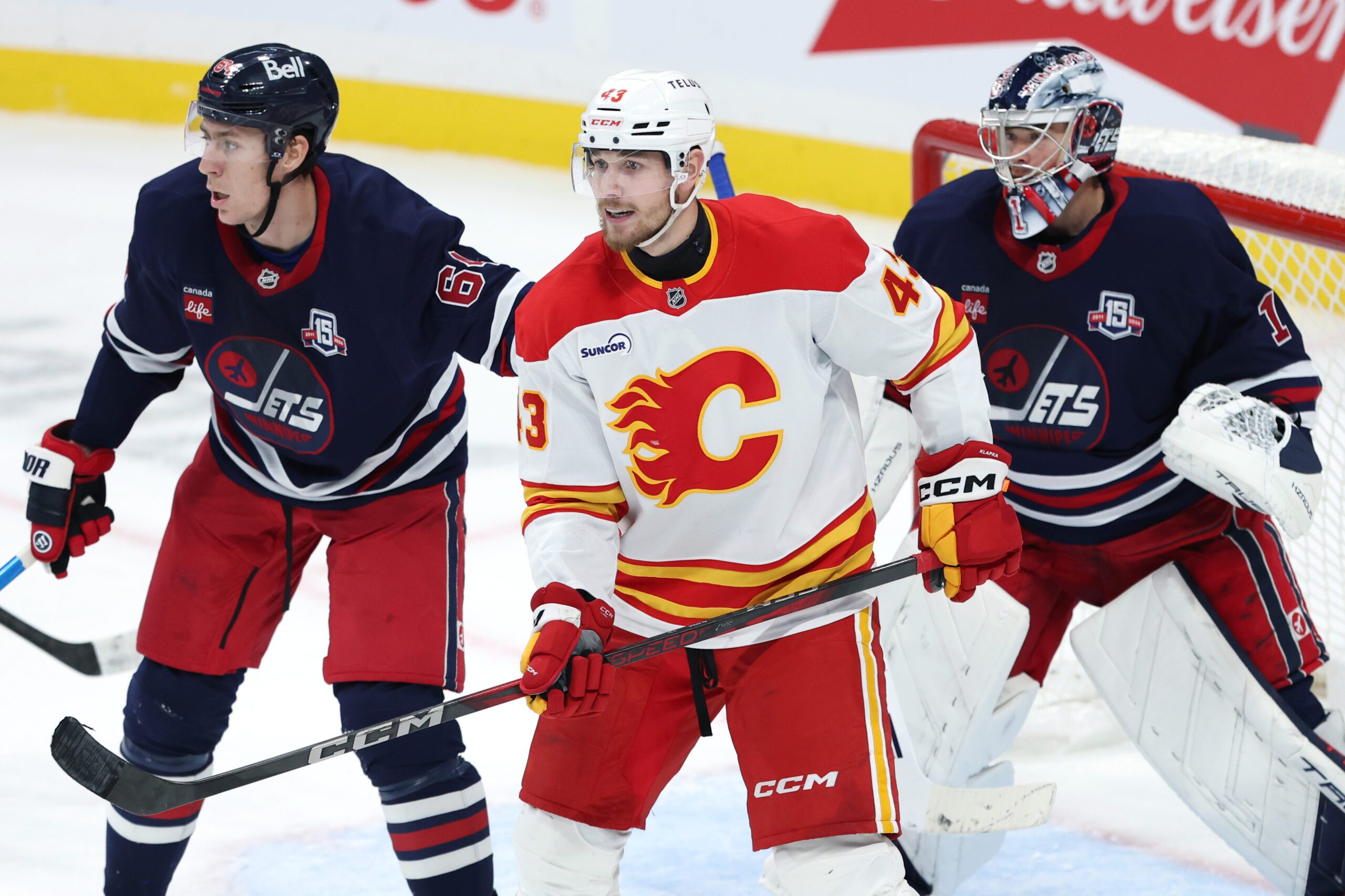 Oct 24, 2025; Winnipeg, Manitoba, CAN; Winnipeg Jets defenseman Logan Stanley (64), Calgary Flames right wing Adam Klapka (43) and Winnipeg Jets goaltender Eric Comrie (1) watch the play in the third period at Canada Life Centre. Mandatory Credit: James Carey Lauder-Imagn Images
