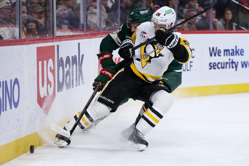 Oct 30, 2025; Saint Paul, Minnesota, USA; Pittsburgh Penguins defenseman Parker Wotherspoon (28) and Minnesota Wild center Yakov Trenin (13) compete for the puck during the second period at Grand Casino Arena. Mandatory Credit: Matt Krohn-Imagn Images