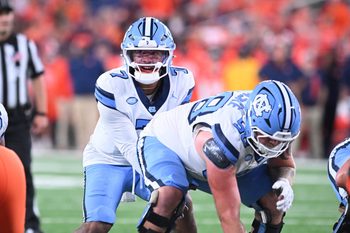 Oct 31, 2025; Syracuse, New York, USA; North Carolina Tar Heels quarterback Gio Lopez (7) with center Austin Blaske (58) at the line of scrimmage in the third quarter against the Syracuse Orange at the JMA Wireless Dome. Mandatory Credit: Mark Konezny-Imagn Images