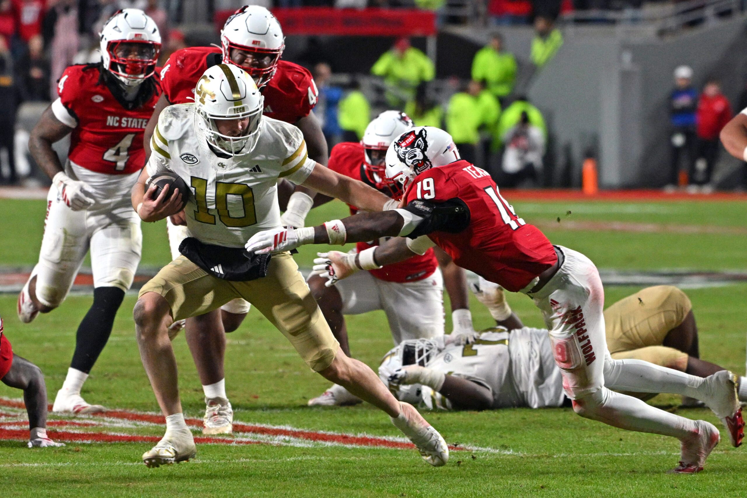 Nov 1, 2025; Raleigh, North Carolina, USA;  Georgia Tech Yellow Jackets quarterback Haynes King (10) controls the ball against North Carolina State Wolfpack saftey Tristan Teasdell (19) during the fourth quarter at Carter-Finley Stadium. Mandatory Credit: Zachary Taft-Imagn Images