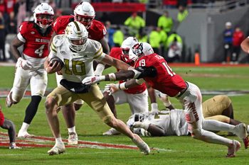 Nov 1, 2025; Raleigh, North Carolina, USA;  Georgia Tech Yellow Jackets quarterback Haynes King (10) controls the ball against North Carolina State Wolfpack saftey Tristan Teasdell (19) during the fourth quarter at Carter-Finley Stadium. Mandatory Credit: Zachary Taft-Imagn Images
