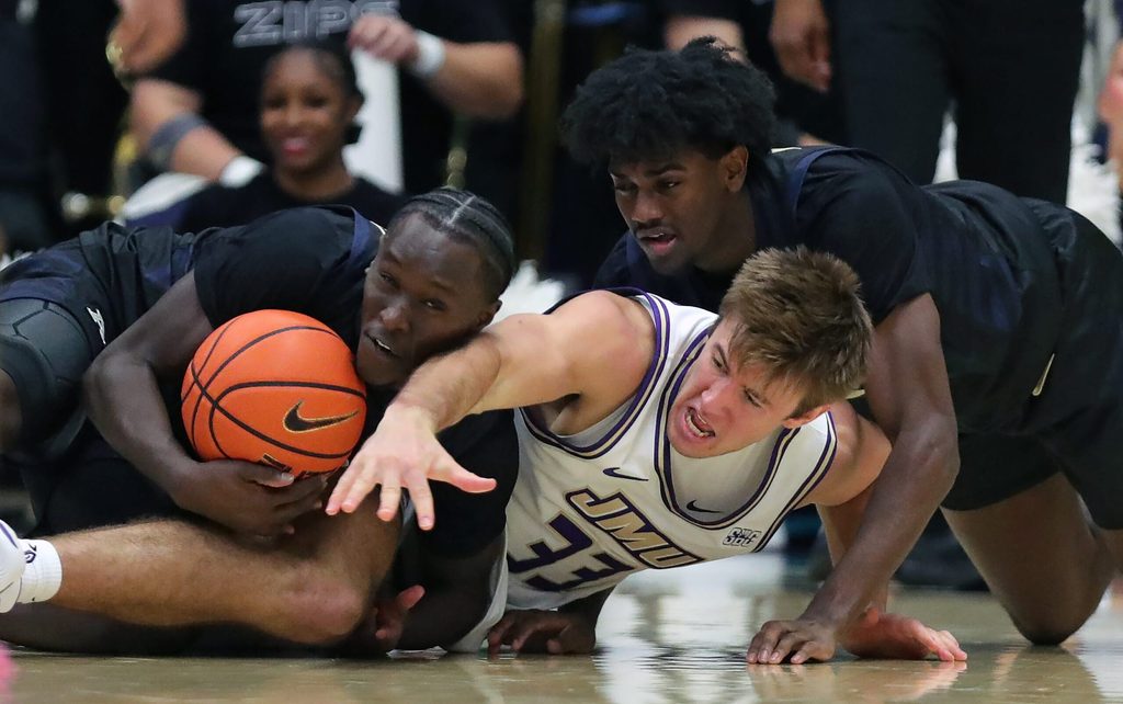 Akron Zips wing Marvin Musiime-Kamali (23) and guard Eric Mahaffey (4) wrestle for possession with James Madison Dukes forward Gabe Newhof (33) during the second half of an NCAA college basketball game at James A. Rhodes Arena, Nov. 3, 2025, in Akron, Ohio