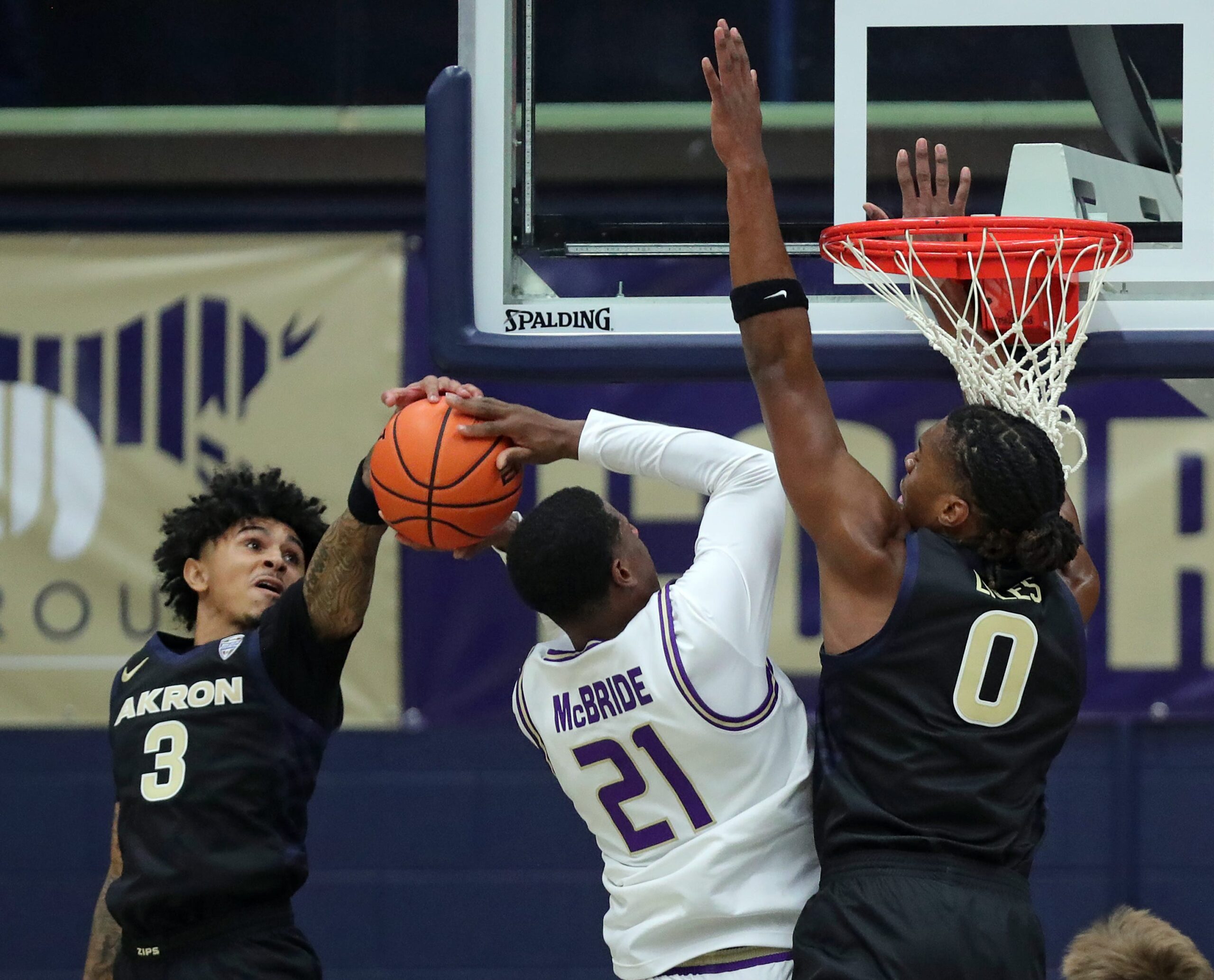 Akron Zips guard Sharron Young (3) and forward Amani Lyles (0) work to block James Madison Dukes forward Justin McBride (21) during the first half of an NCAA college basketball game at James A. Rhodes Arena, Nov. 3, 2025, in Akron, Ohio