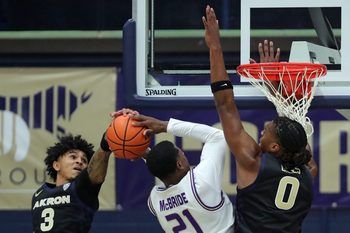 Akron Zips guard Sharron Young (3) and forward Amani Lyles (0) work to block James Madison Dukes forward Justin McBride (21) during the first half of an NCAA college basketball game at James A. Rhodes Arena, Nov. 3, 2025, in Akron, Ohio