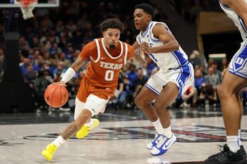 Nov 4, 2025; Charlotte, North Carolina, USA; Texas Longhorns guard Jordan Pope (0) drives the ball around Duke Blue Devils guard Caleb Foster (1) during the second half of the Dick Vitale’s Invitational game at Spectrum Center. Mandatory Credit: Cory Knowlton-Imagn Images