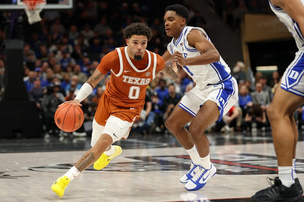 Nov 4, 2025; Charlotte, North Carolina, USA; Texas Longhorns guard Jordan Pope (0) drives the ball around Duke Blue Devils guard Caleb Foster (1) during the second half of the Dick Vitale’s Invitational game at Spectrum Center. Mandatory Credit: Cory Knowlton-Imagn Images
