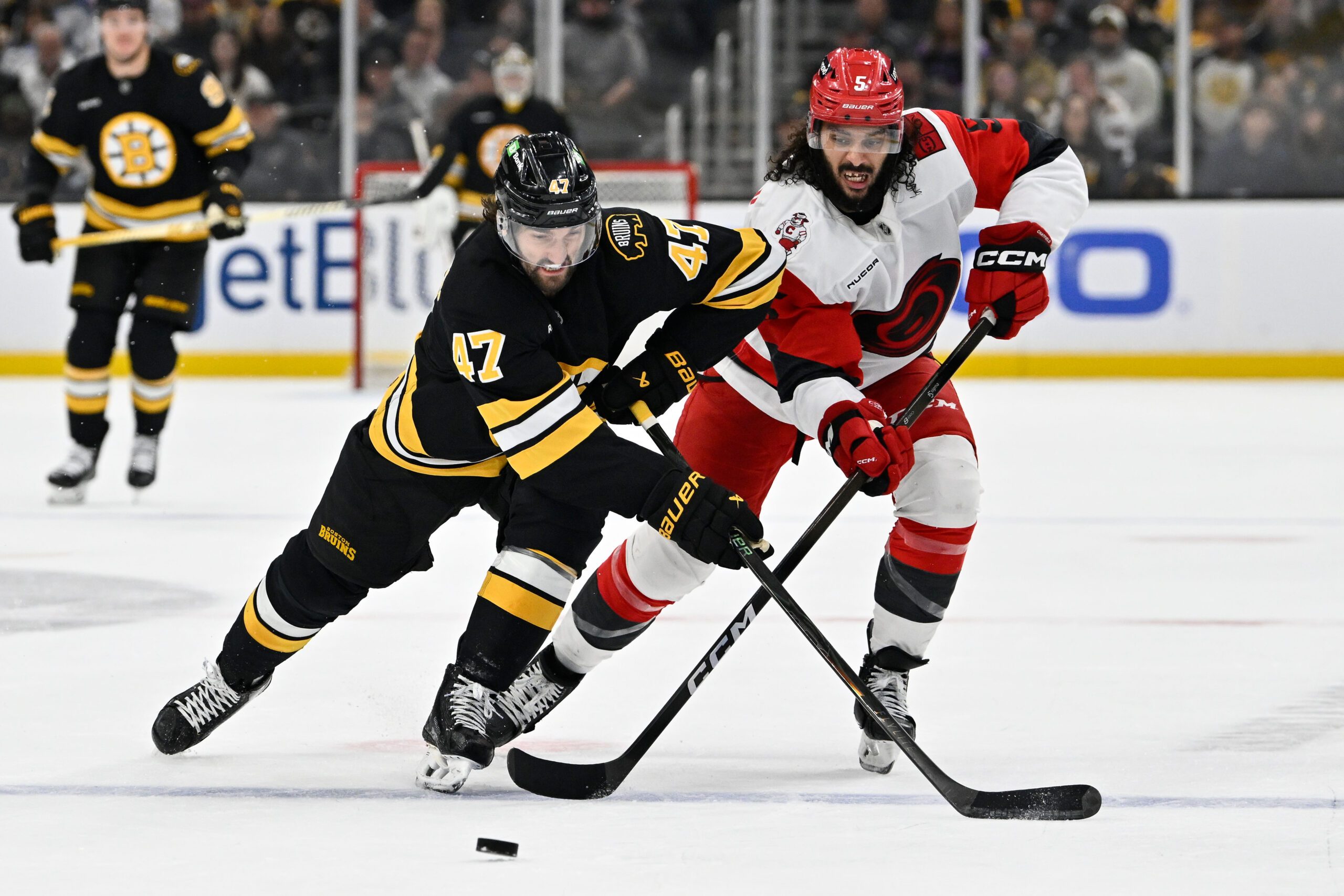 Nov 1, 2025; Boston, Massachusetts, USA; Boston Bruins center Mark Kastelic (47) and Carolina Hurricanes defenseman Jalen Chatfield (5) battle for control of the puck during the third period at TD Garden. Mandatory Credit: Eric Canha-Imagn Images