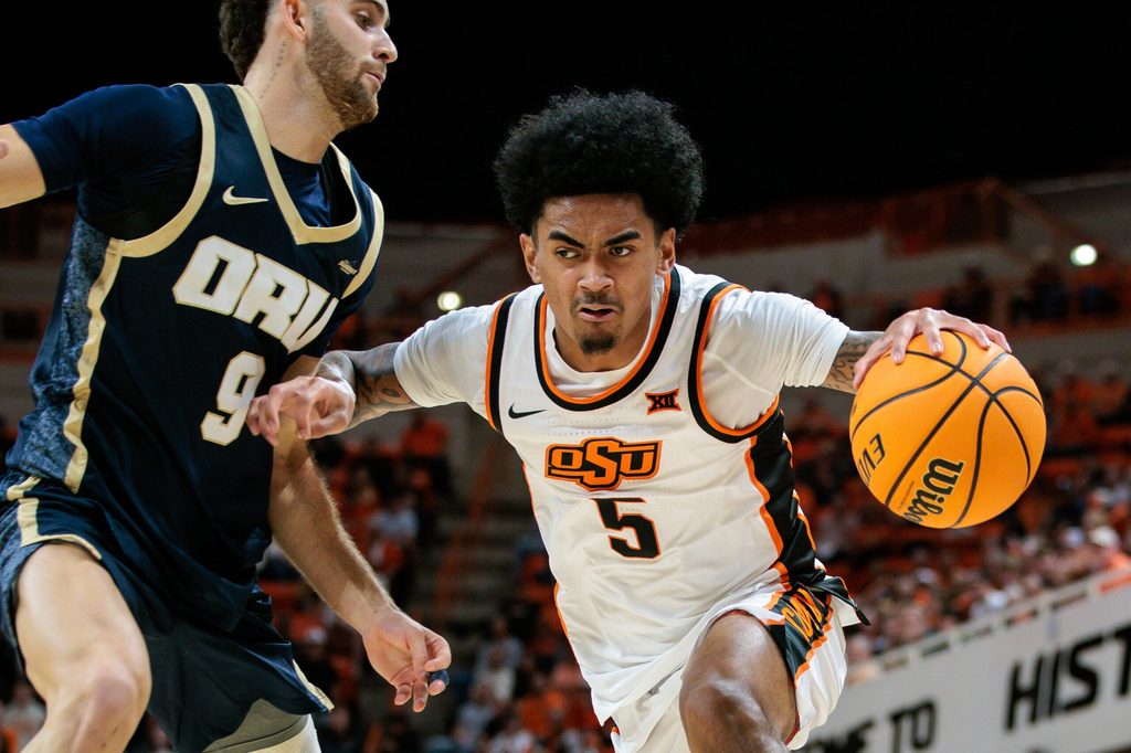 Nov 4, 2025; Stillwater, Oklahoma, USA; Oklahoma State Cowboys guard Vyctorius Miller (5) drives to the basket around Oral Roberts Golden Eagles forward Ofri Naveh (9) during the first half at Gallagher-Iba Arena. Mandatory Credit: William Purnell-Imagn Images
