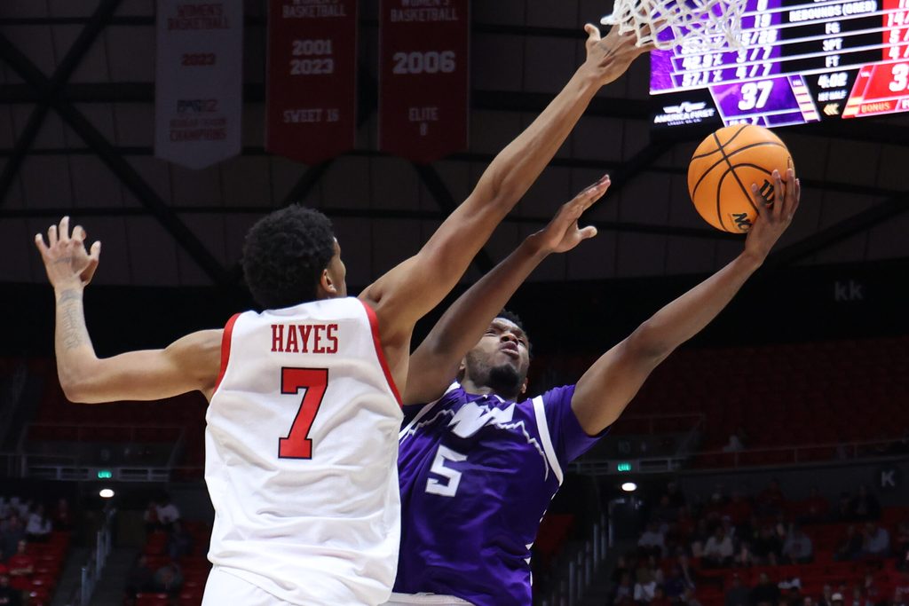 Nov 8, 2025; Salt Lake City, Utah, USA; Weber State Wildcats forward Nigel Burris (5) lays the ball up against Utah Utes forward Josh Hayes (7) during the first half at Jon M. Huntsman Center. Mandatory Credit: Rob Gray-Imagn Images
