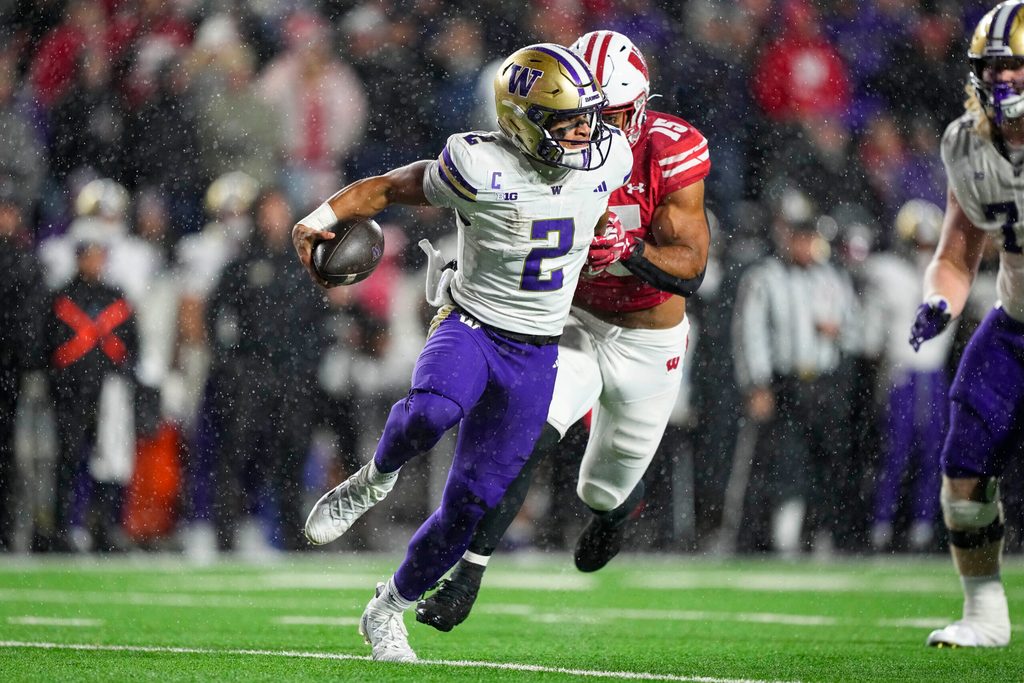 Nov 8, 2025; Madison, Wisconsin, USA; Washington Huskies quarterback Demond Williams Jr. (2) scrambles under pressure from Wisconsin Badgers linebacker Sebastian Cheeks (15) during the third quarter at Camp Randall Stadium. Mandatory Credit: Jeff Hanisch-Imagn Images
