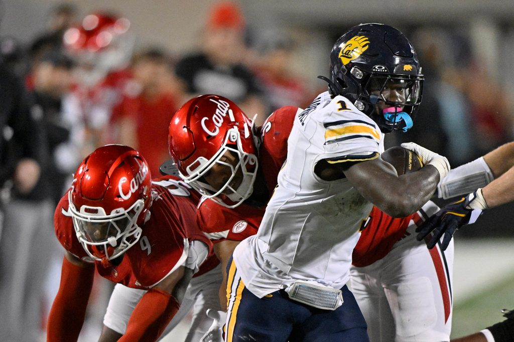 Nov 8, 2025; Louisville, Kentucky, USA; California Golden Bears running back Kendrick Raphael (1) runs the ball against Louisville Cardinals defensive back Antonio Watts (9) and linebacker T.J. Quinn (34) in overtime at L&N Federal Credit Union Stadium. California defeated Louisville 29-26. Mandatory Credit: Jamie Rhodes-Imagn Images