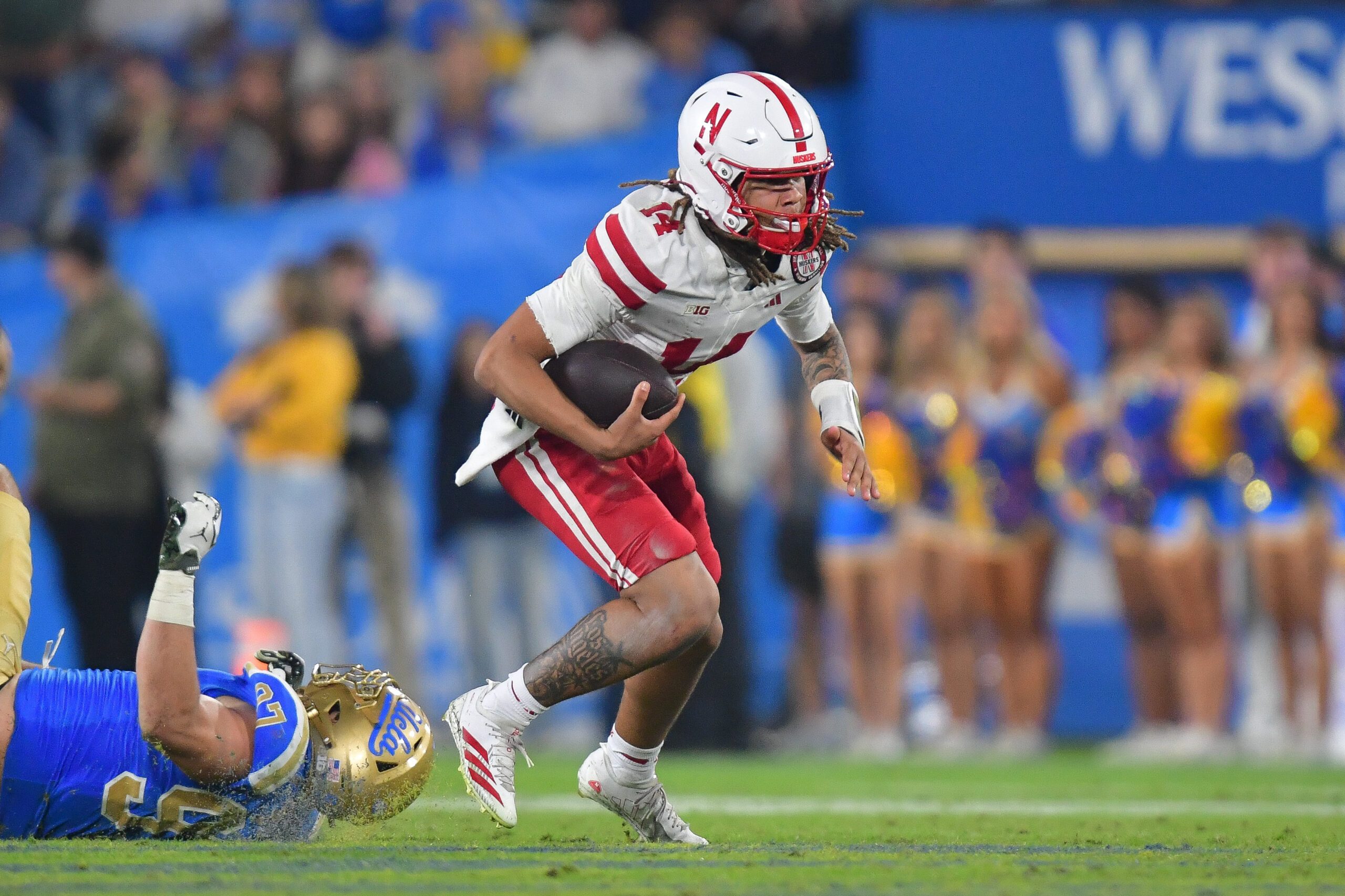 Nov 8, 2025; Pasadena, California, USA; Nebraska Cornhuskers quarterback TJ Lateef (14) runs the ball ahead of UCLA Bruins defensive lineman Jacob Busic (97) during the second half at the Rose Bowl. Mandatory Credit: Gary A. Vasquez-Imagn Images