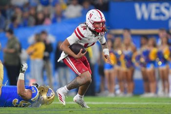 Nov 8, 2025; Pasadena, California, USA; Nebraska Cornhuskers quarterback TJ Lateef (14) runs the ball ahead of UCLA Bruins defensive lineman Jacob Busic (97) during the second half at the Rose Bowl. Mandatory Credit: Gary A. Vasquez-Imagn Images