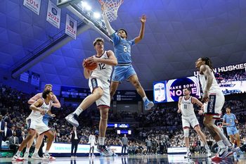 Nov 10, 2025; Storrs, Connecticut, USA; UConn Huskies center Eric Reibe (12) grabs the rebound against Columbia Lions guard Miles Franklin (24) in the first half at Harry A. Gampel Pavilion. Mandatory Credit: David Butler II-Imagn Images