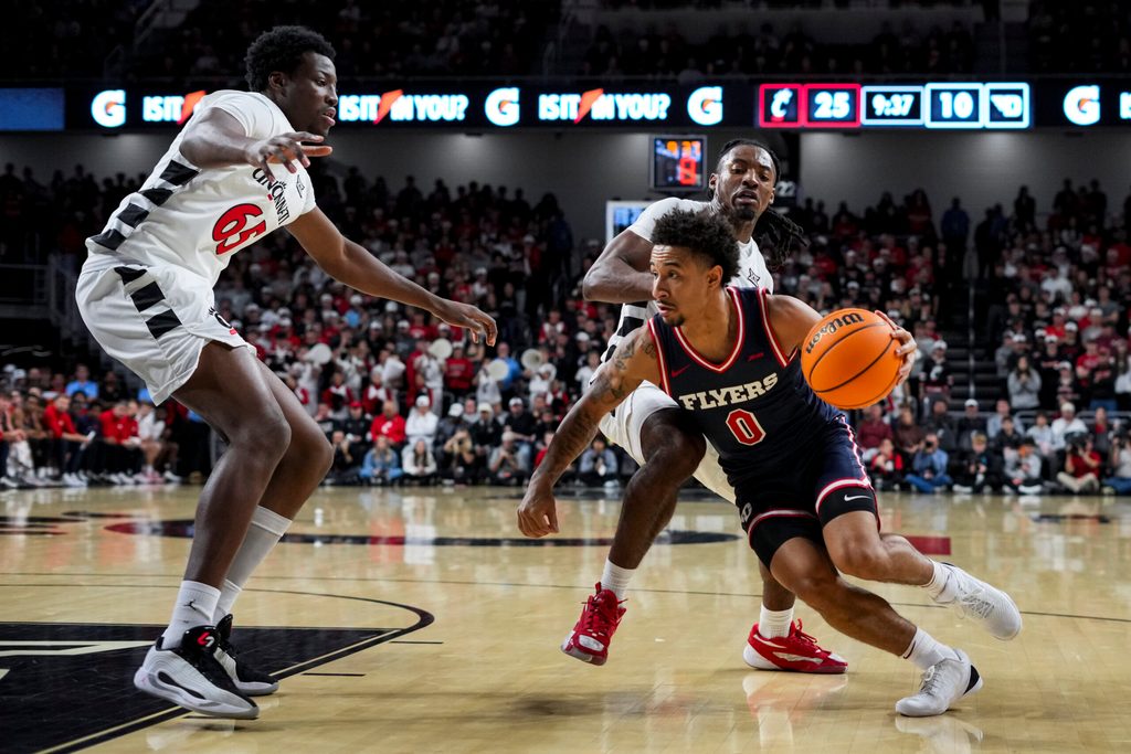 Nov 11, 2025; Cincinnati, Ohio, USA; Dayton Flyers guard Javon Bennett (0) drives to the basket against Cincinnati Bearcats guard Day Day Thomas (1) and forward Halvine Dzellat (65) in the first half at Fifth Third Arena. Mandatory Credit: Aaron Doster-Imagn Images
