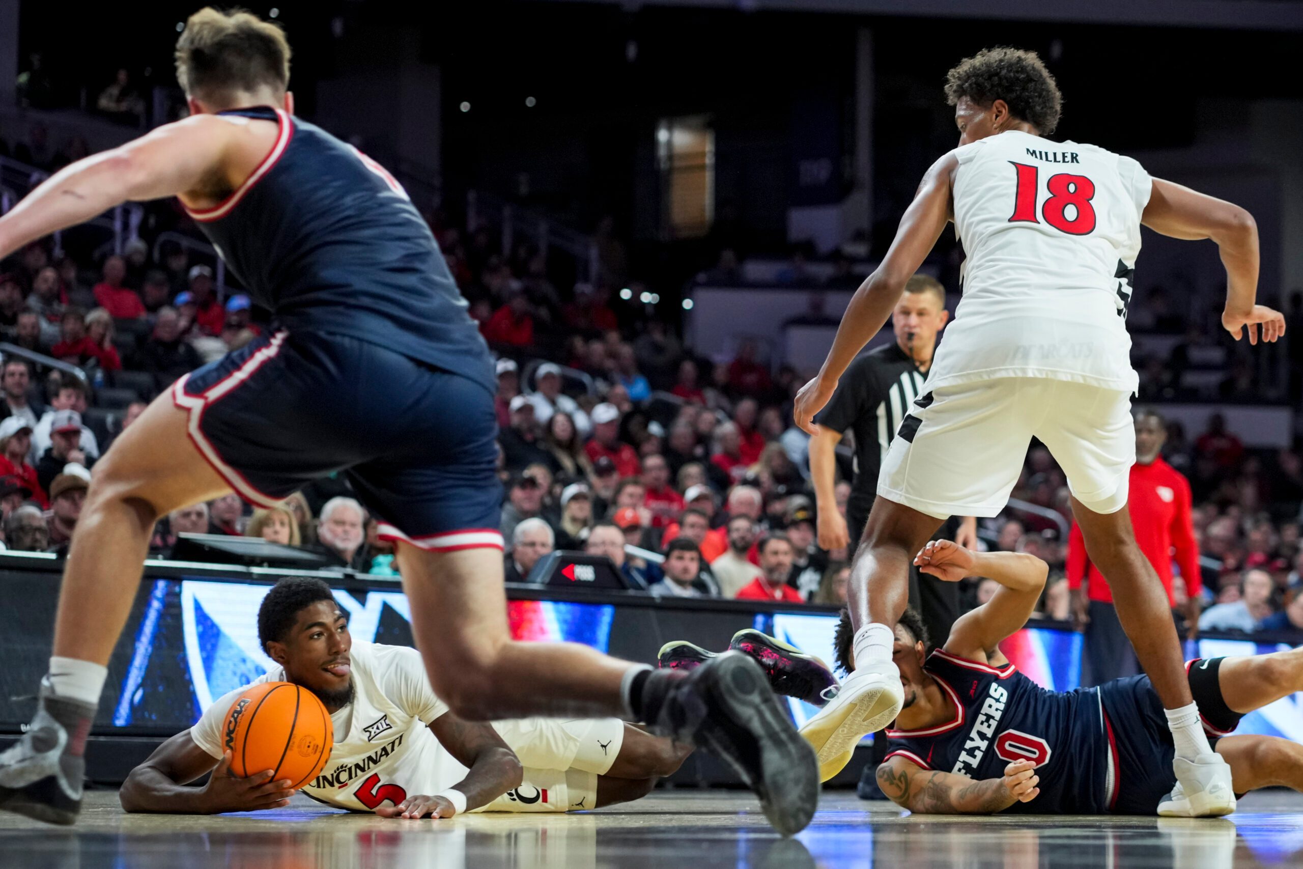 Nov 11, 2025; Cincinnati, Ohio, USA; Cincinnati Bearcats guard Sencire Harris (5) jumps on the loose ball against Dayton Flyers guard Javon Bennett (0) in the second half at Fifth Third Arena. Mandatory Credit: Aaron Doster-Imagn Images