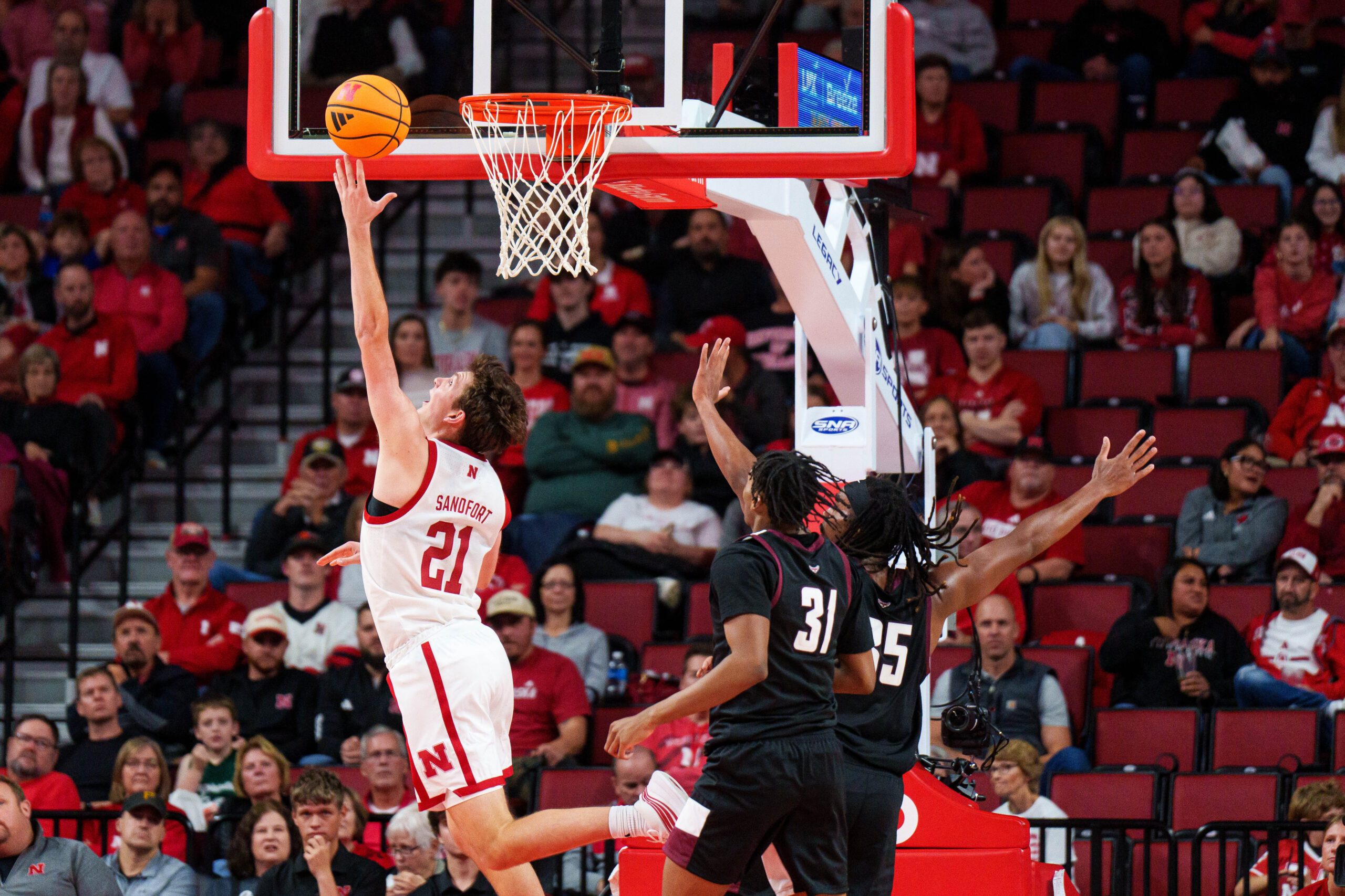 Nov 11, 2025; Lincoln, Nebraska, USA; Nebraska Cornhuskers forward Pryce Sandfort (21) shoots the ball against Maryland Eastern Shore Hawks forward Maurio Hanson Jr. (31) and forward Christopher Flippin (35) during the second half at Pinnacle Bank Arena. Mandatory Credit: Dylan Widger-Imagn Images