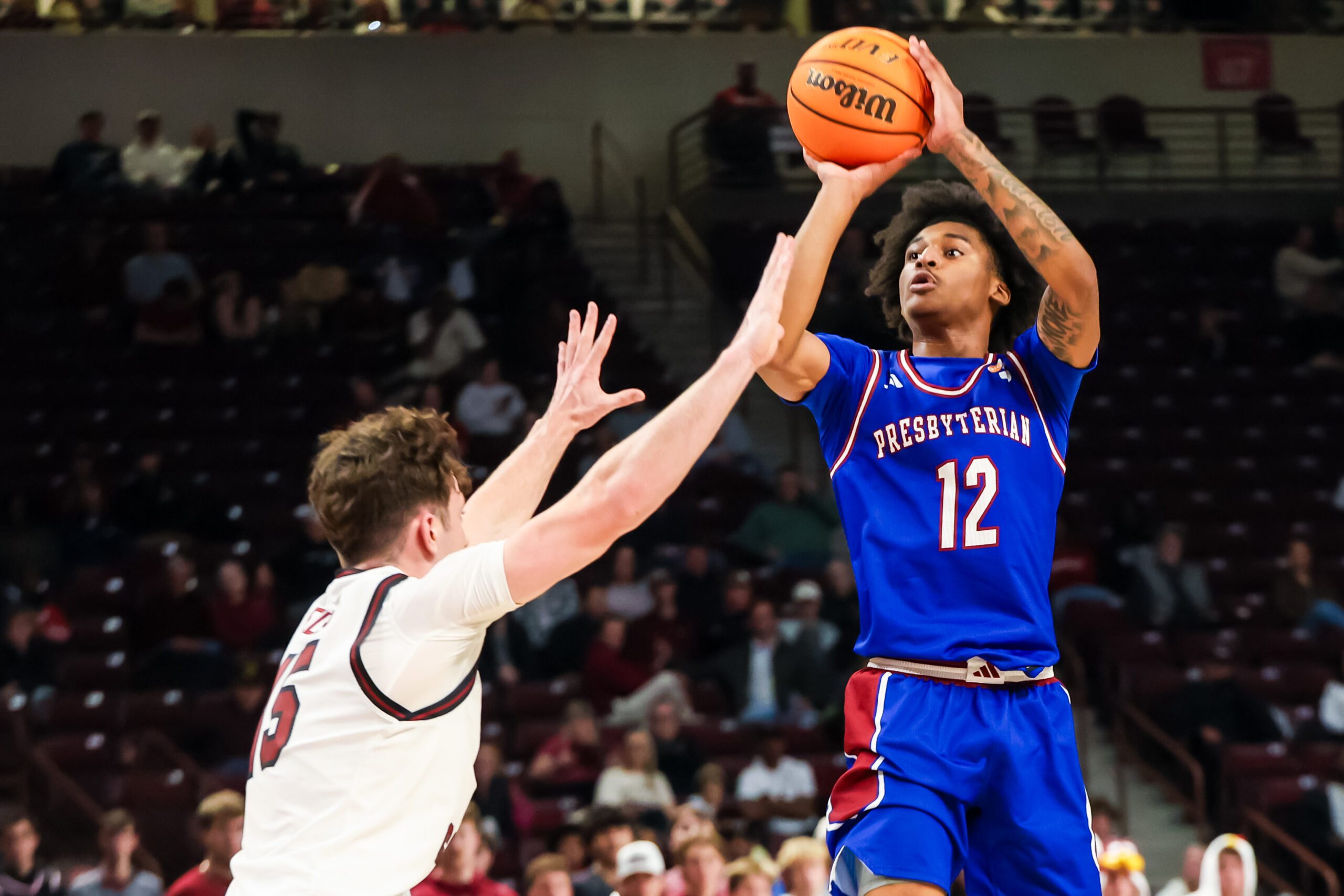 Nov 12, 2025; Columbia, South Carolina, USA; Presbyterian Blue Hose guard Carl Parrish (12) shoots over South Carolina Gamecocks guard Eli Ellis (15) in the second half at Colonial Life Arena. Mandatory Credit: Jeff Blake-Imagn Images